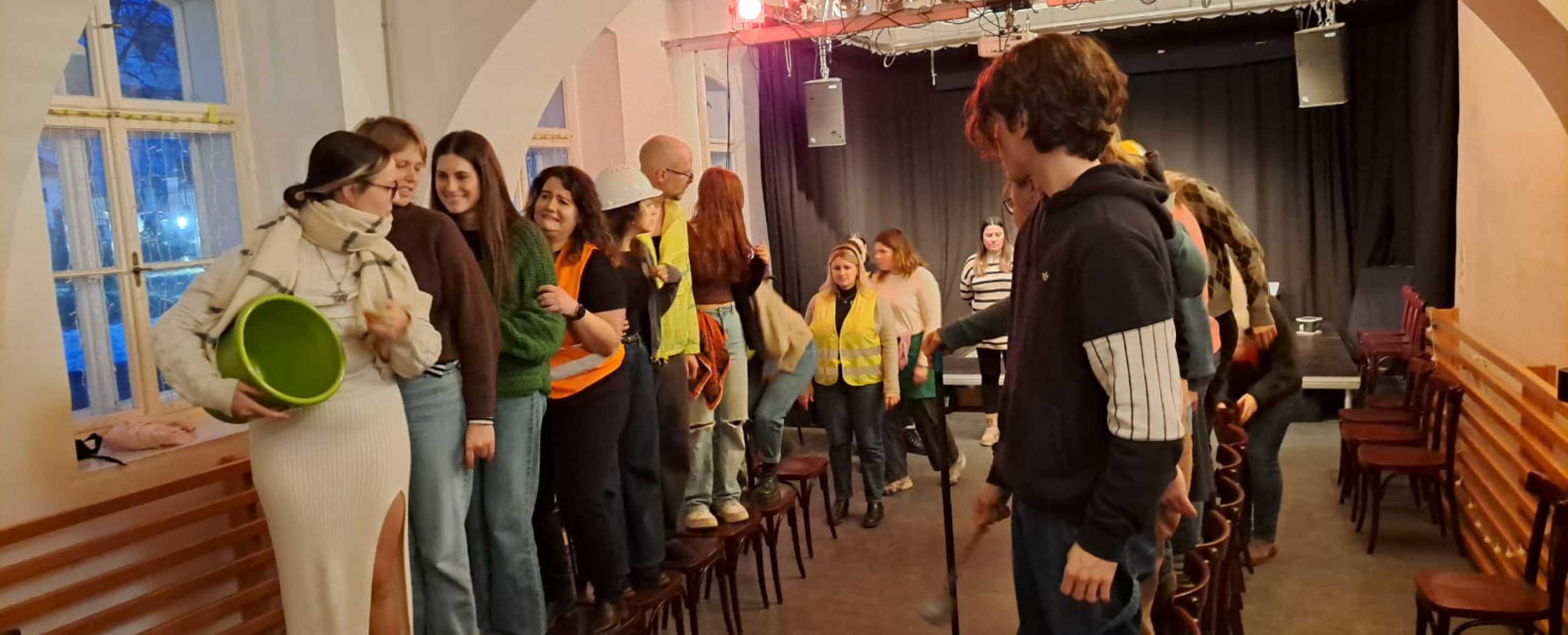 Studierendengruppe auf Sesseln stehend